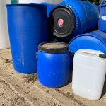 Some blue barrels and a white 25l water container